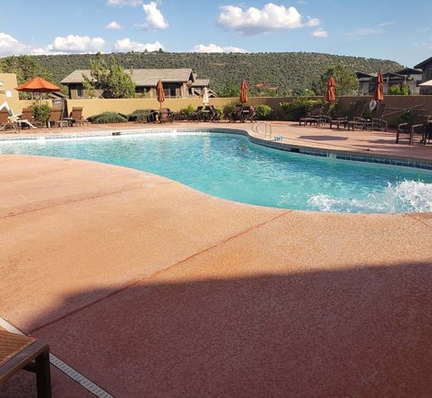 Outdoor swimming pool with chairs and tables on a sunny day.