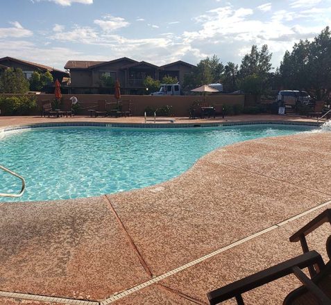 Resort-style swimming pool with lounge chairs and umbrellas on a sunny day.