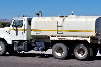 White tank truck labeled "NON-POTABLE WATER" parked on asphalt with a clear sky.